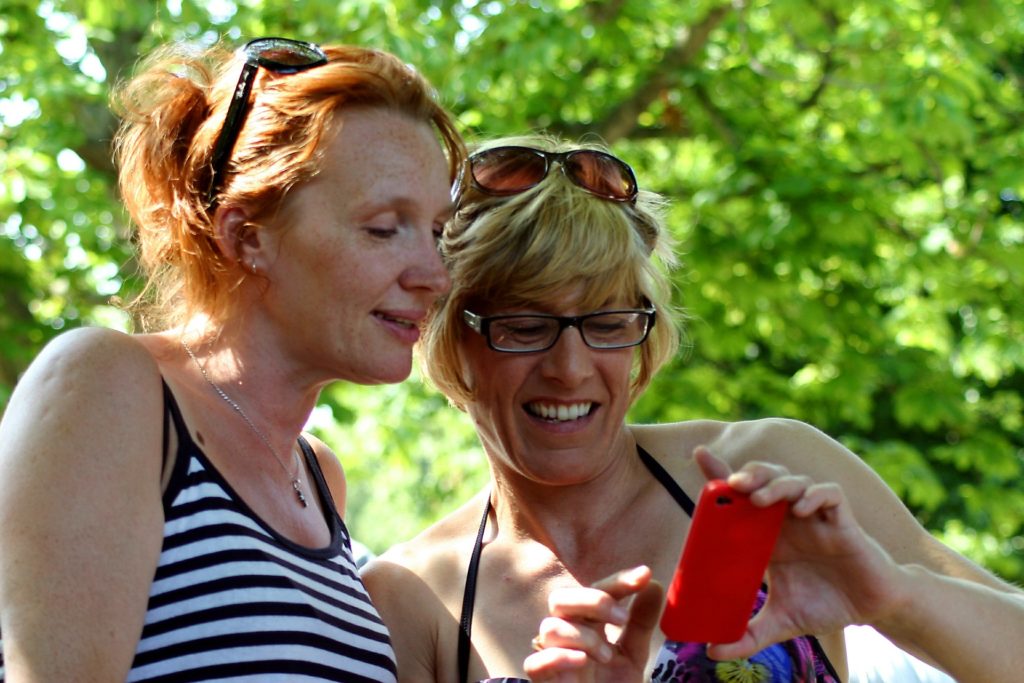 two women looking at a cell phone checking the results of online dental marketing